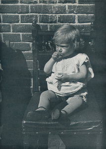 716625 Portret van een klein meisje zittend op een stoel op straat, vermoedelijk in de Jordaan te Amsterdam.